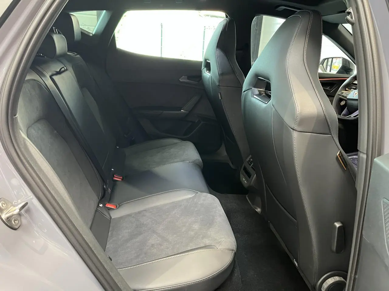 Vue intérieure côté gauche des sièges arrière en cuir et alcantara gris clair du CUPRA Formentor 2025 avec détails couture contrastés.