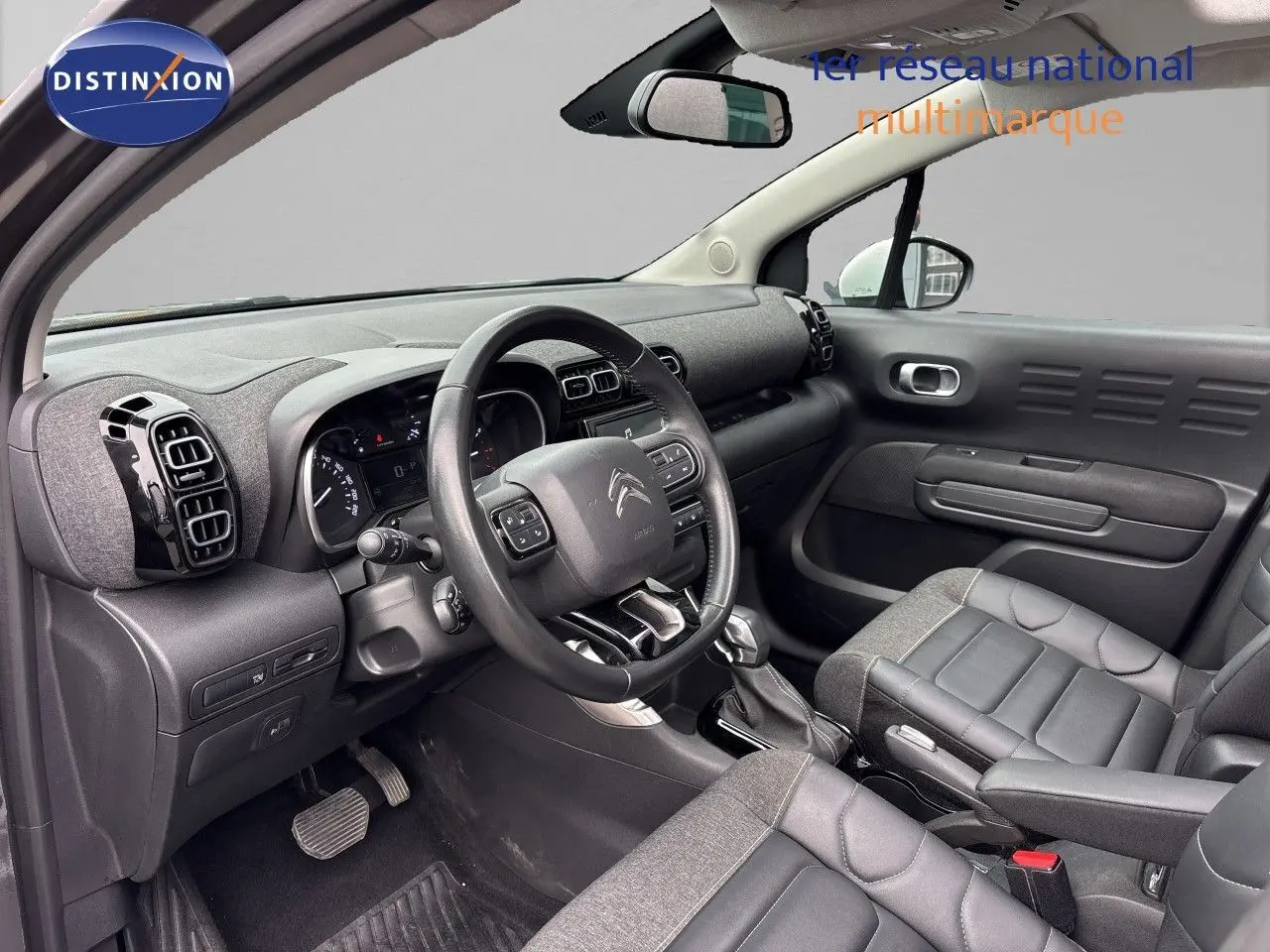 Vue intérieure côté conducteur de la Citroën C3 Aircross gris platinium, avec tableau de bord et sièges en tissu et cuir.