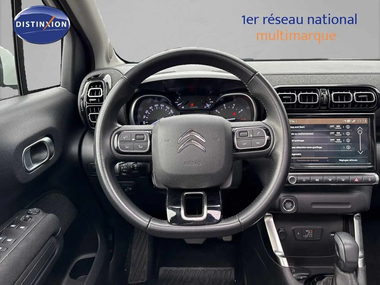 Vue intérieure centrée sur le volant noir et le tableau de bord numérique d'une Citroën C3 Aircross gris platinium.