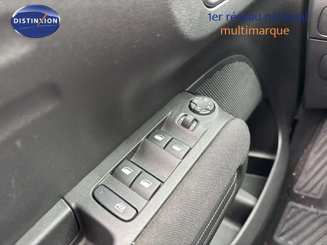 Gros plan sur les commandes des vitres électriques côté conducteur d'une Citroën C3 Aircross gris platinium, intérieur noir.