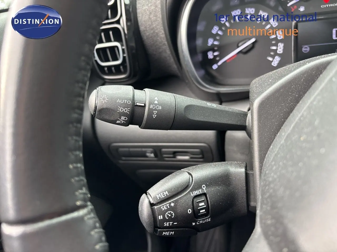 Gros plan sur les commandes au volant d'une Citroën C3 Aircross gris platinium, mettant en valeur les fonctions de régulateur et éclairage.