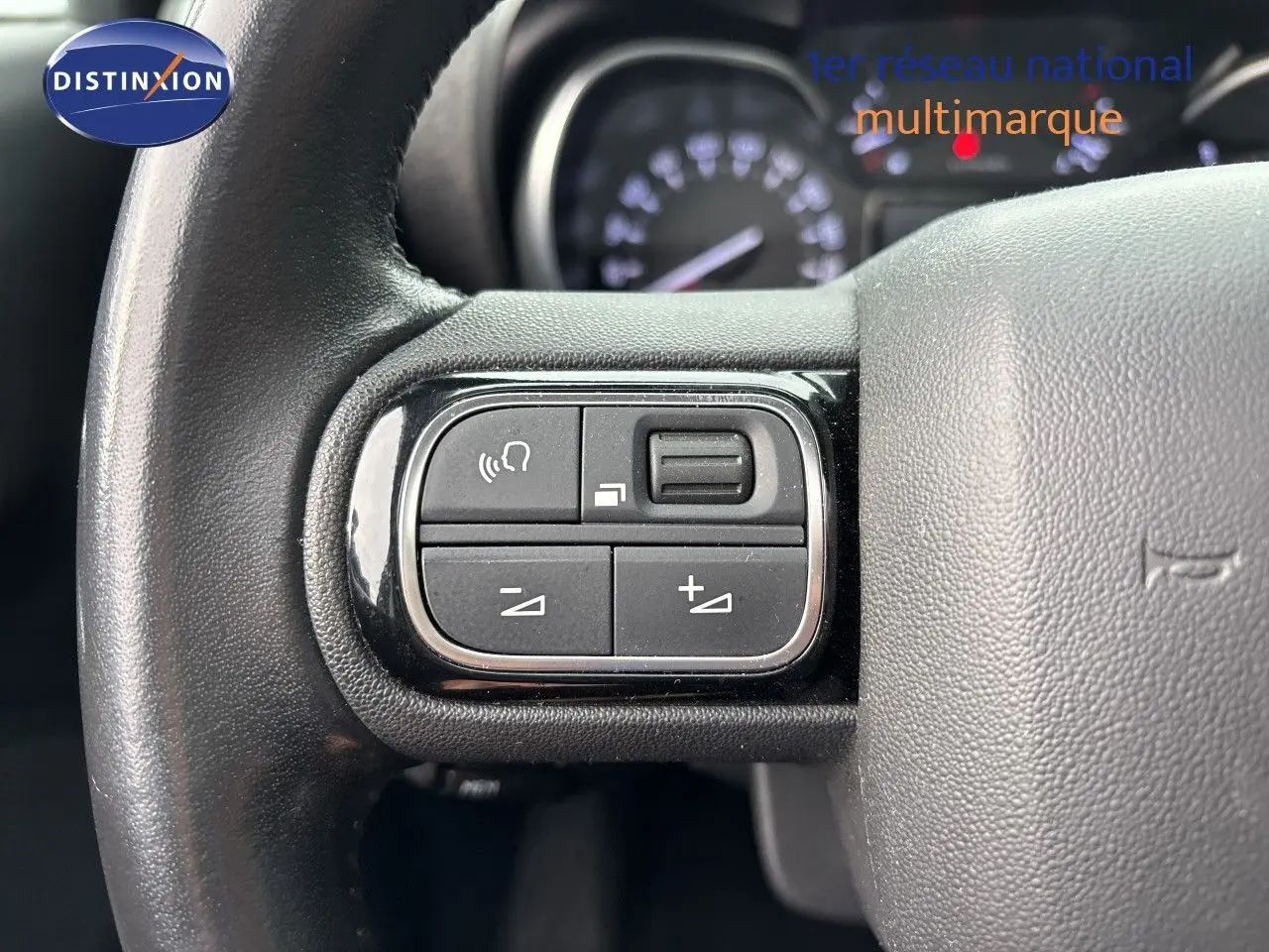 Gros plan sur les commandes gauche du volant en cuir noir du Citroën C3 Aircross 2021, avec tableau de bord flou en arrière-plan.