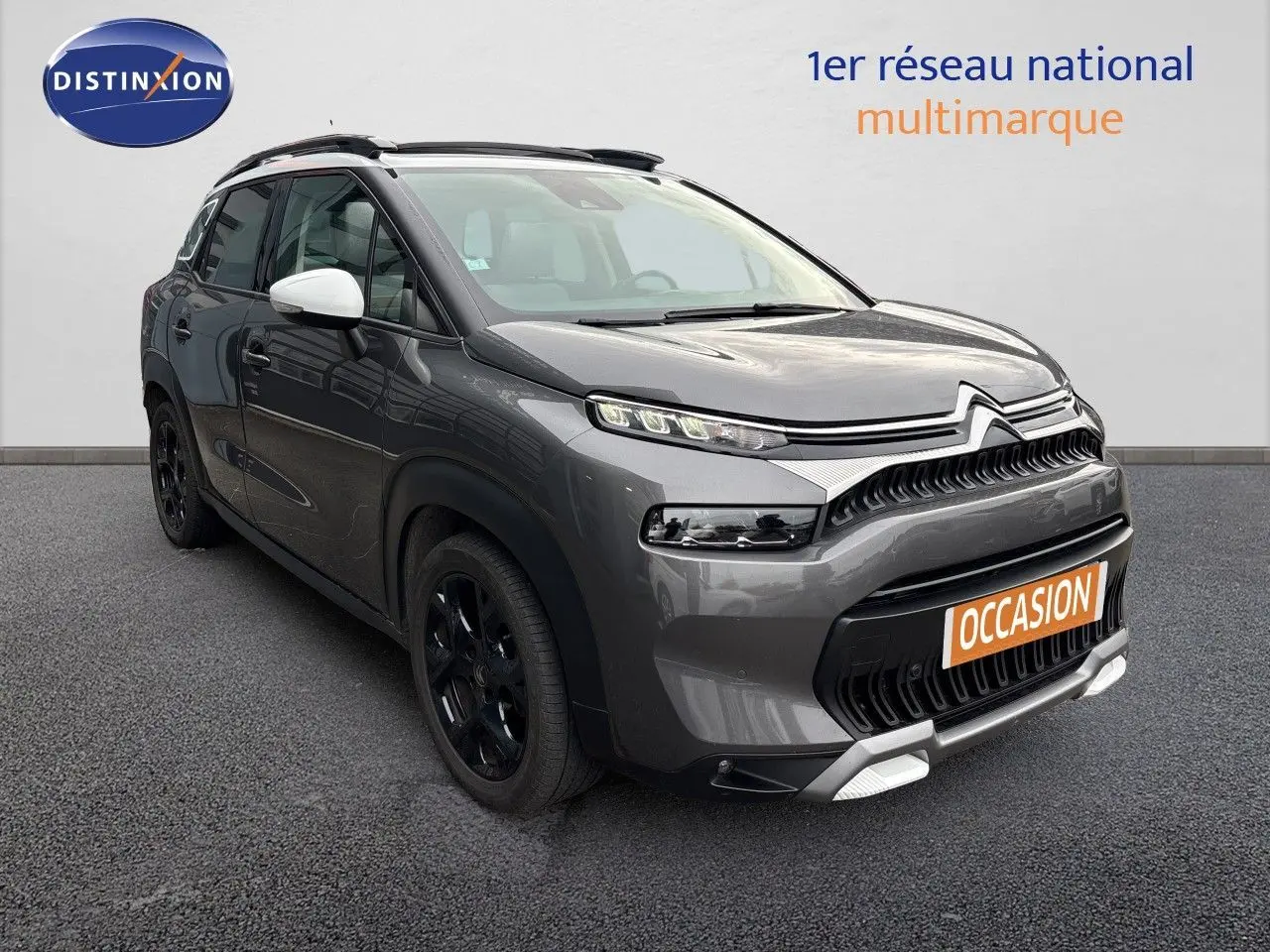 Citroën C3 Aircross gris platinium en 3/4 avant droit, avec jantes noires et coques de rétroviseurs blanches.