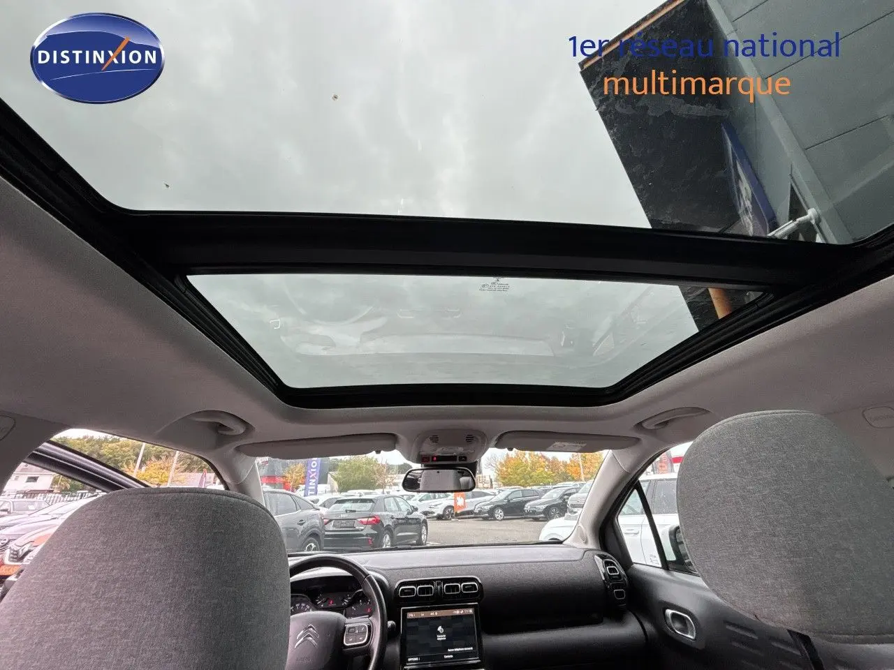 Vue intérieure avant du Citroën C3 Aircross gris platinium 2021, mettant en valeur le toit panoramique et le tableau de bord.