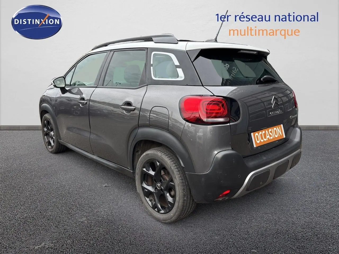 Vue 3/4 arrière droite d'un Citroën C3 Aircross gris platinium avec toit blanc et jantes noires distinctives.
