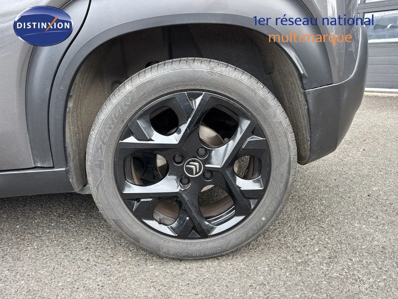Gros plan sur la roue arrière droite noire brillante du Citroën C3 Aircross gris platinium, avec logo Citroën central.