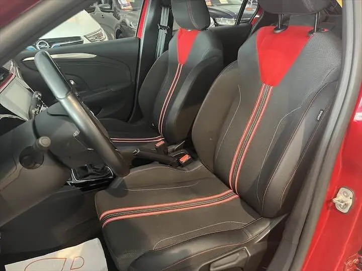 Vue intérieure côté conducteur de l'Opel Corsa rouge Kardio avec sièges tissu noir et rouge à bandes centrales contrastées.