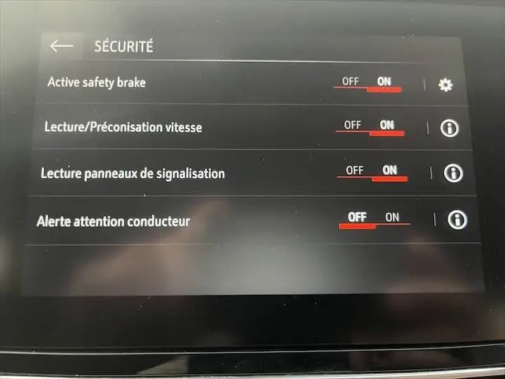 Écran tactile intérieur affichant les réglages de sécurité d'une Opel Corsa rouge Kardio, version 2021.