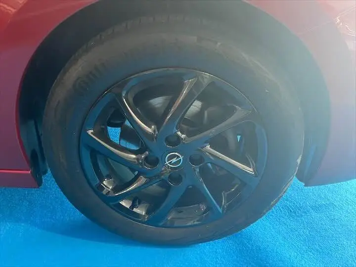 Gros plan sur la roue avant gauche de l'Opel Corsa rouge Kardio, mettant en valeur la jante noire au design moderne.