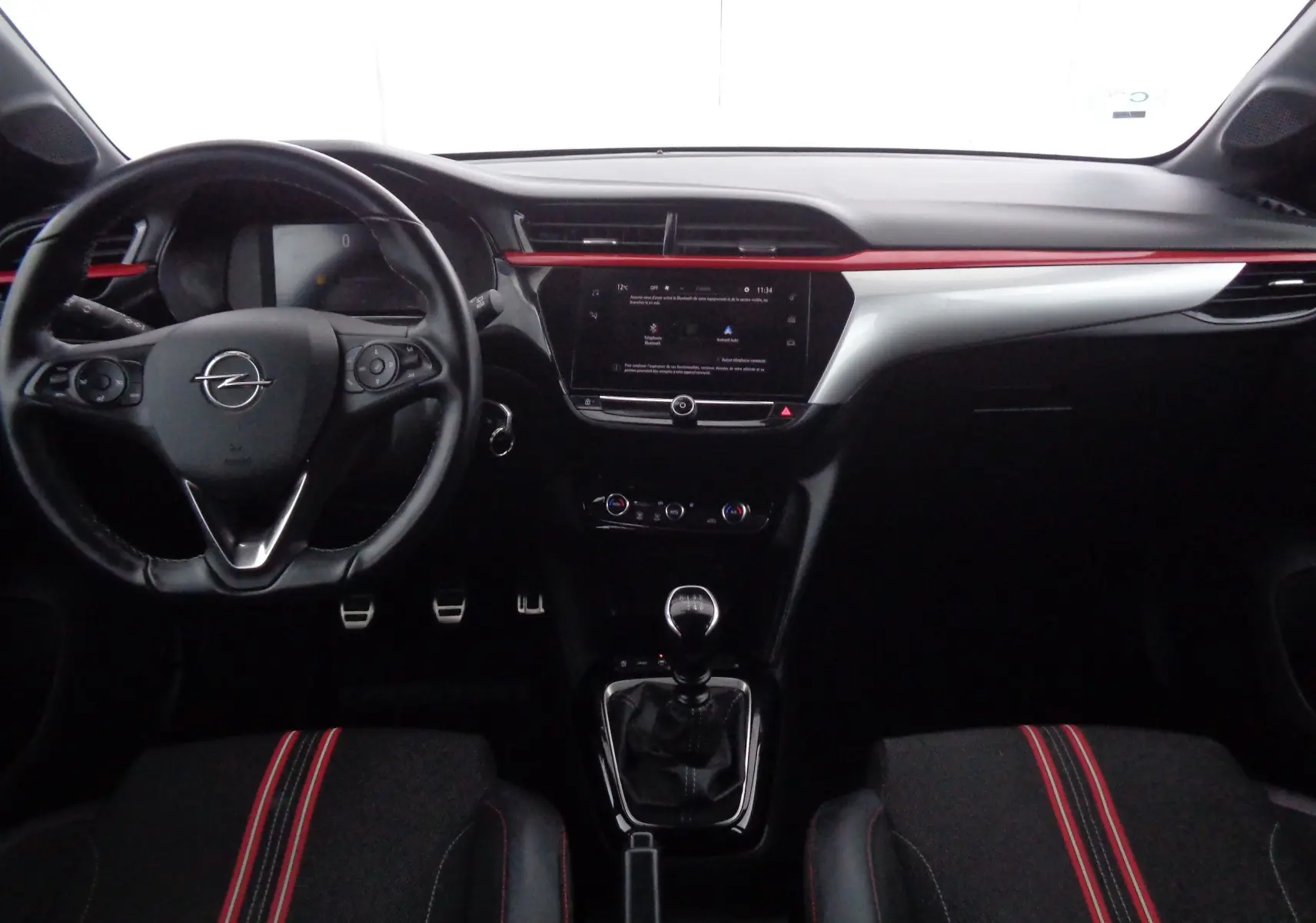 Vue intérieure avant de l’Opel Corsa 1.2T 100 CH GS-Line 2021 avec volant, tableau de bord noir et touches rouges.