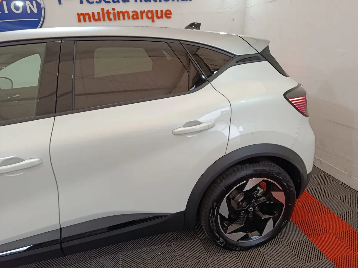 Vue latérale côté droit du Renault Captur blanc 2025, mettant en valeur la porte arrière et la roue arrière au design moderne.