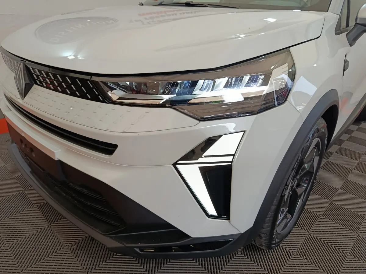 Gros plan sur l'avant droit blanc du Renault Captur 2025 avec phares LED et calandre moderne noire et blanche.