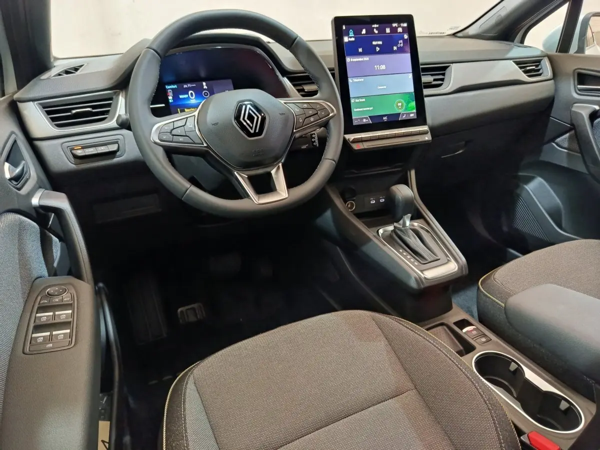 Intérieur Renault Captur 2025 vu côté conducteur, volant cuir, écran tactile vertical et console centrale noire.