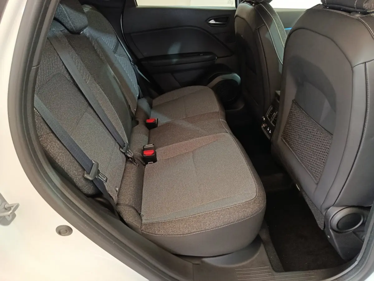 Vue côté gauche des sièges arrière gris foncé du Renault Captur blanc 2025, avec ceintures et poche de rangement au dos des sièges avant.