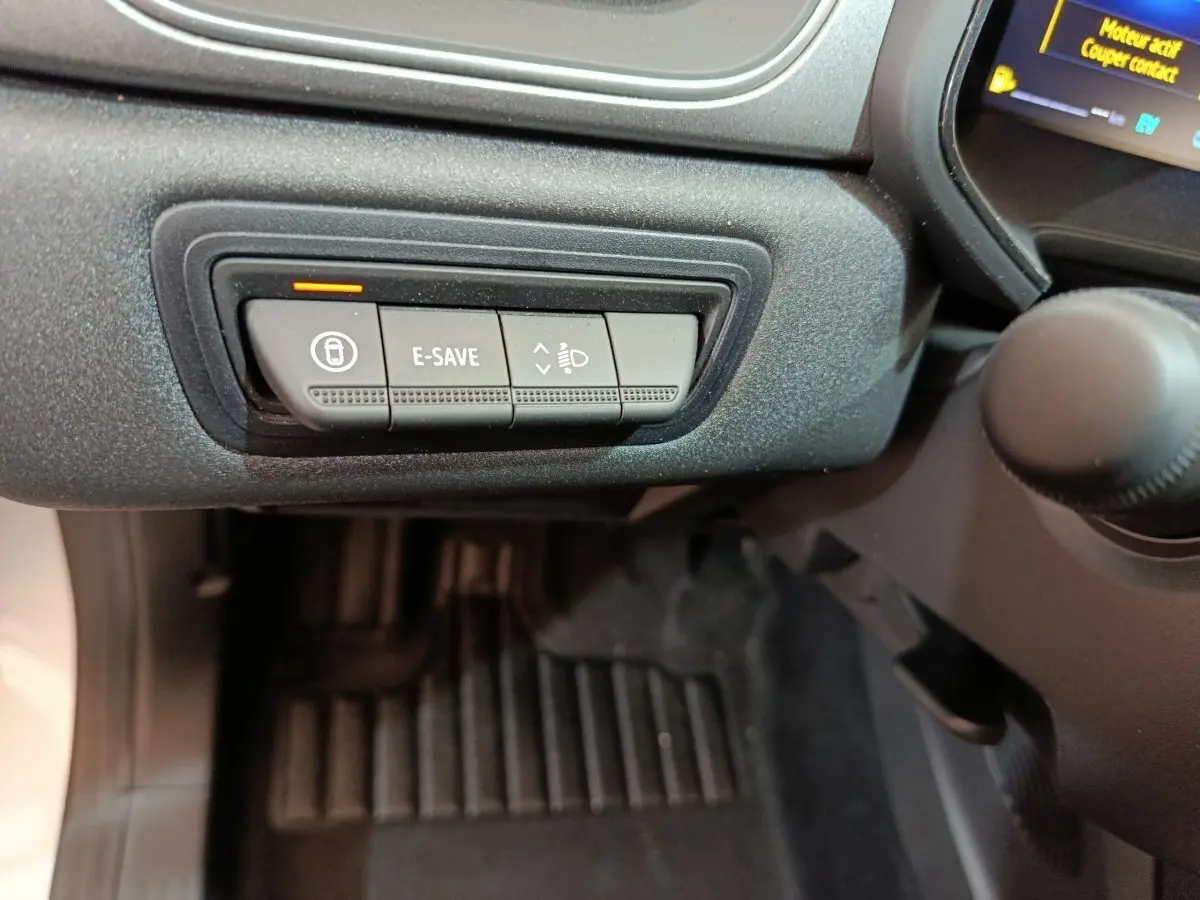 Gros plan sur les commandes sous le tableau de bord côté conducteur du Renault Captur blanc 2025 hybride.