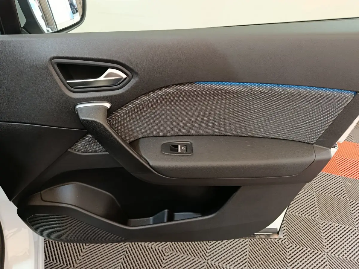 Panneau de porte intérieur côté gauche du Renault Captur blanc 2025 avec éclairage d'ambiance bleu et commande de vitre.