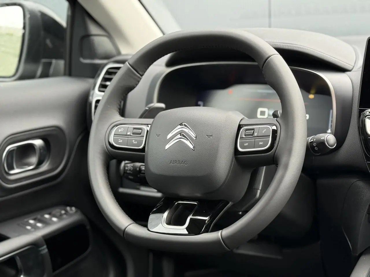 Vue rapprochée du volant cuir noir avec commandes intégrées du tableau de bord du Citroën C5 Aircross 2025.