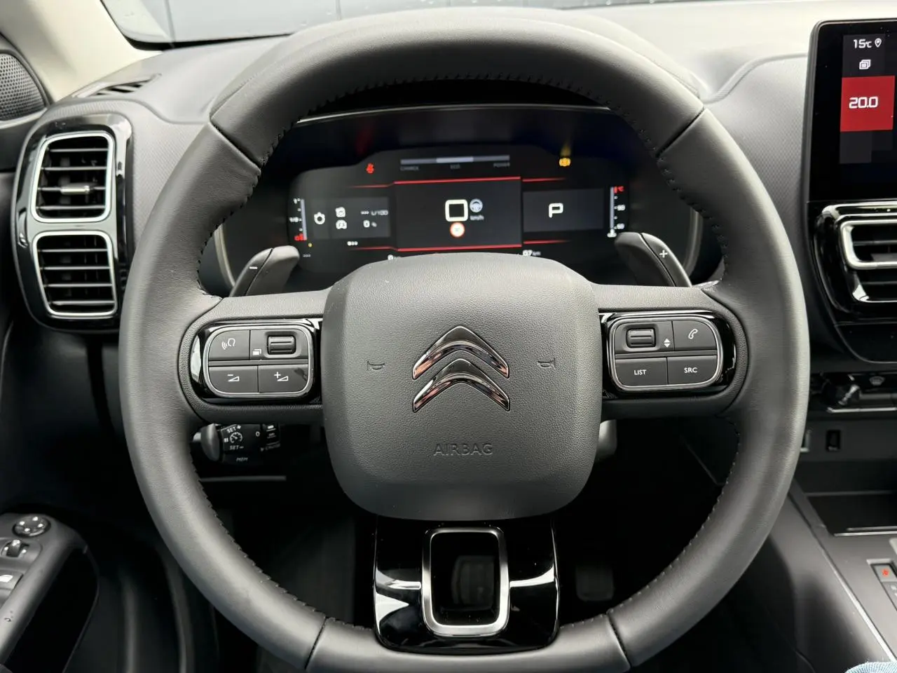 Vue rapprochée du volant noir du Citroën C5 Aircross 2025 avec commandes intégrées et tableau de bord numérique.