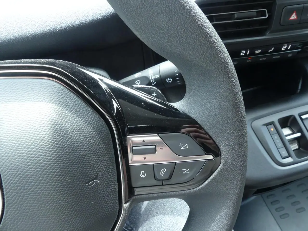 Gros plan sur le volant multifonctions côté droit du Peugeot Partner blanc avec commandes audio et vocales intégrées.