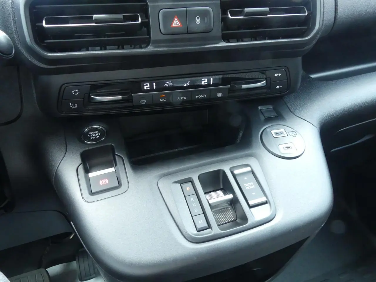 Gros plan sur la console centrale noire du Peugeot Partner 2025 avec commandes climatisation et boîte auto compacte.