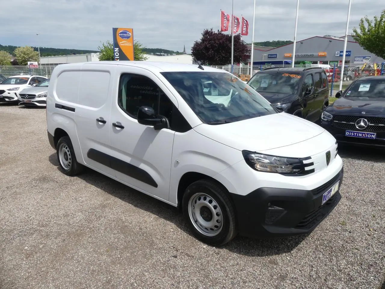 Vue 3/4 avant droite d'un utilitaire Peugeot Partner blanc avec protections latérales noires et jantes tôle grises.