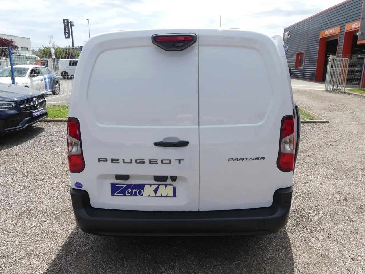 Vue arrière d'un utilitaire Peugeot Partner blanc avec portes battantes et pare-chocs noir mat.