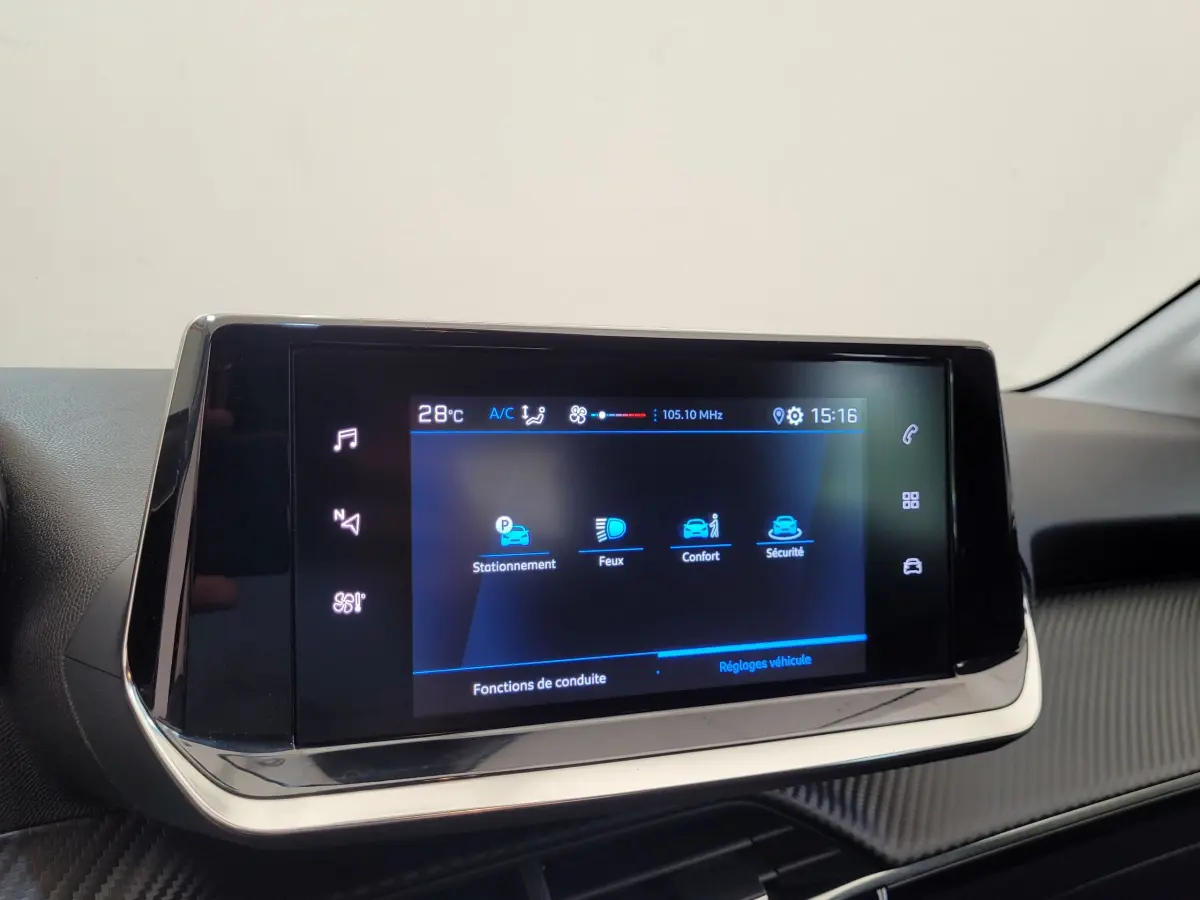 Écran tactile central de la Peugeot 208 gris foncé, affichant les réglages de conduite et sécurité.