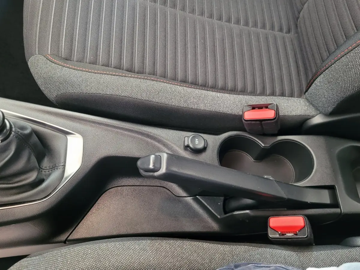 Vue rapprochée de la console centrale de la Peugeot 208 gris foncé, montrant frein à main manuel et porte-gobelets.