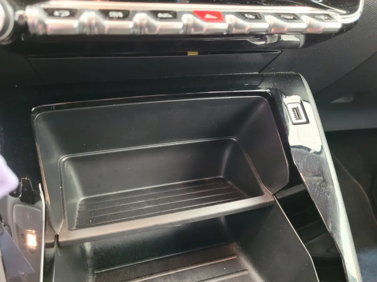 Rangement central ouvert avec port USB visible sur le côté dans l'habitacle d'une Peugeot 208 gris foncé.