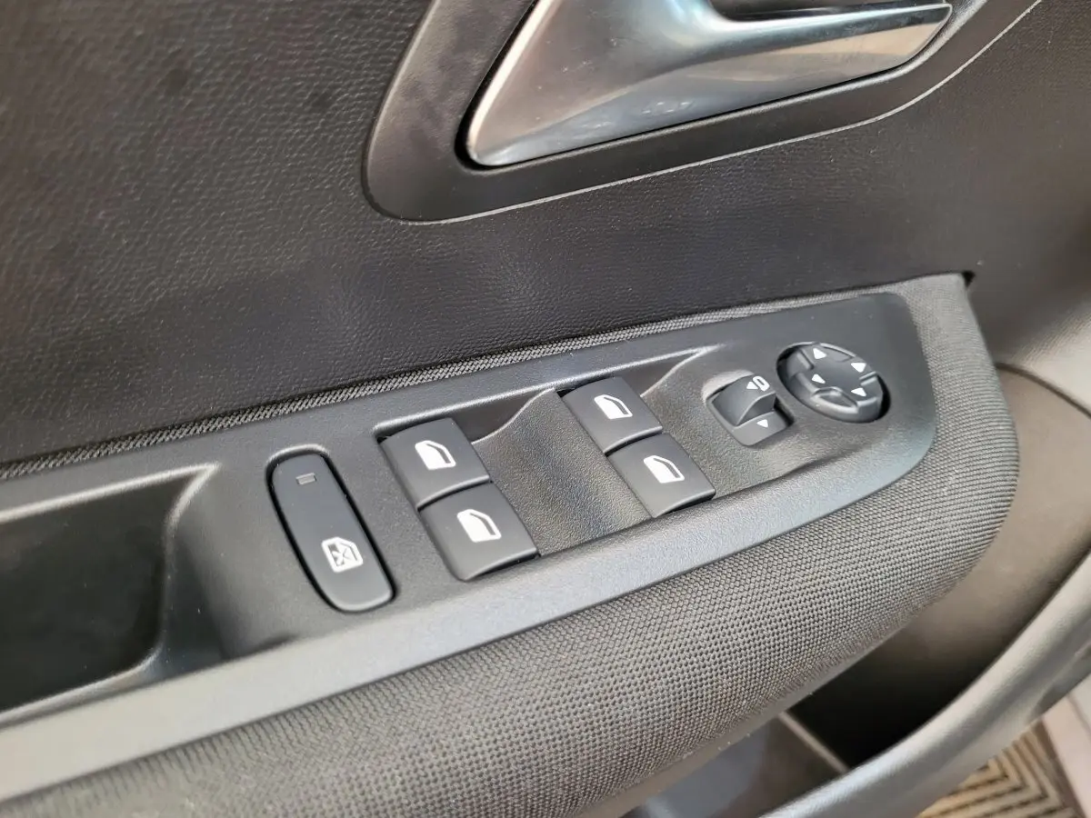 Gros plan sur les commandes des vitres électriques côté conducteur de la Peugeot 208 gris foncé 2023 Active Pack.
