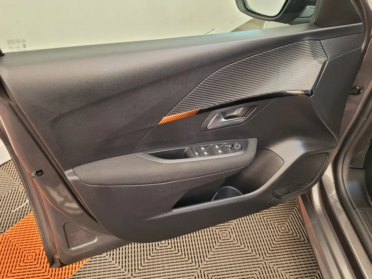 Vue côté intérieur de la porte avant gauche de la Peugeot 208 gris foncé avec insert décoratif noir et orange.
