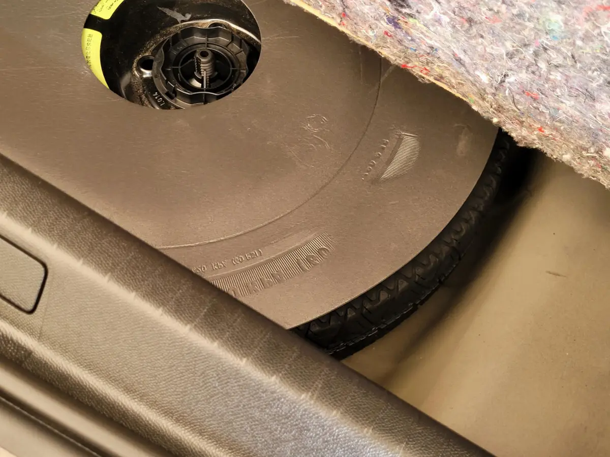 Gros plan sur la roue de secours sous le tapis de coffre d'une Peugeot 208 gris foncé, version BlueHDi 2023.