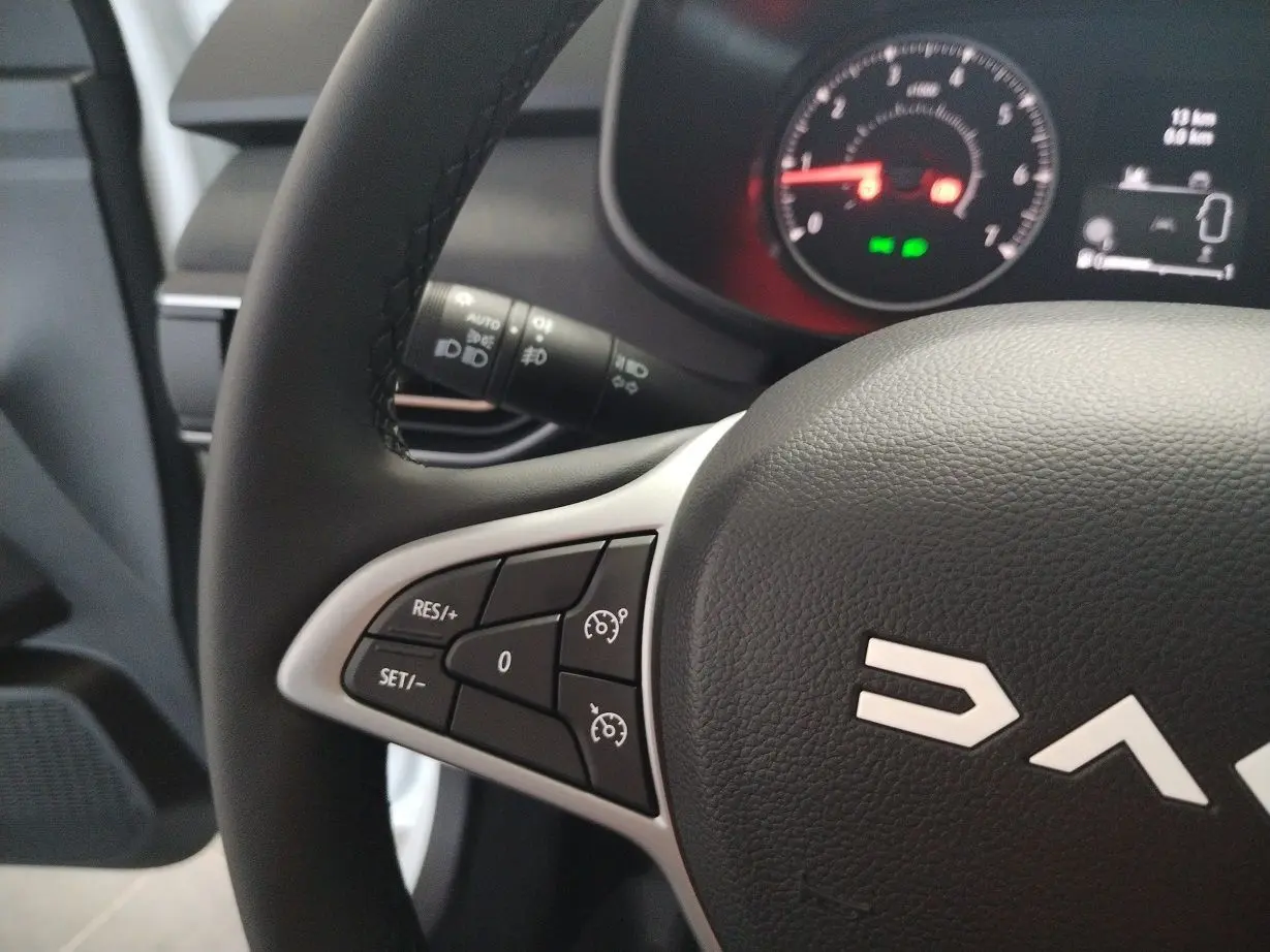 Gros plan sur le volant noir de la Dacia Jogger 2025, montrant les commandes de régulateur de vitesse à gauche.