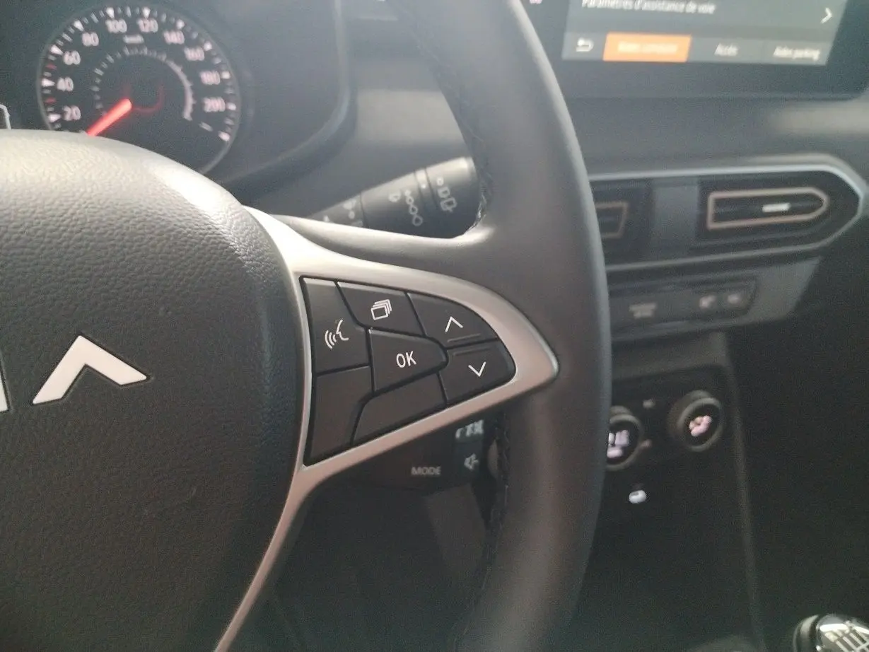 Gros plan sur la partie droite du volant du Dacia Jogger 2025 avec commandes multifonctions et tableau de bord noir.