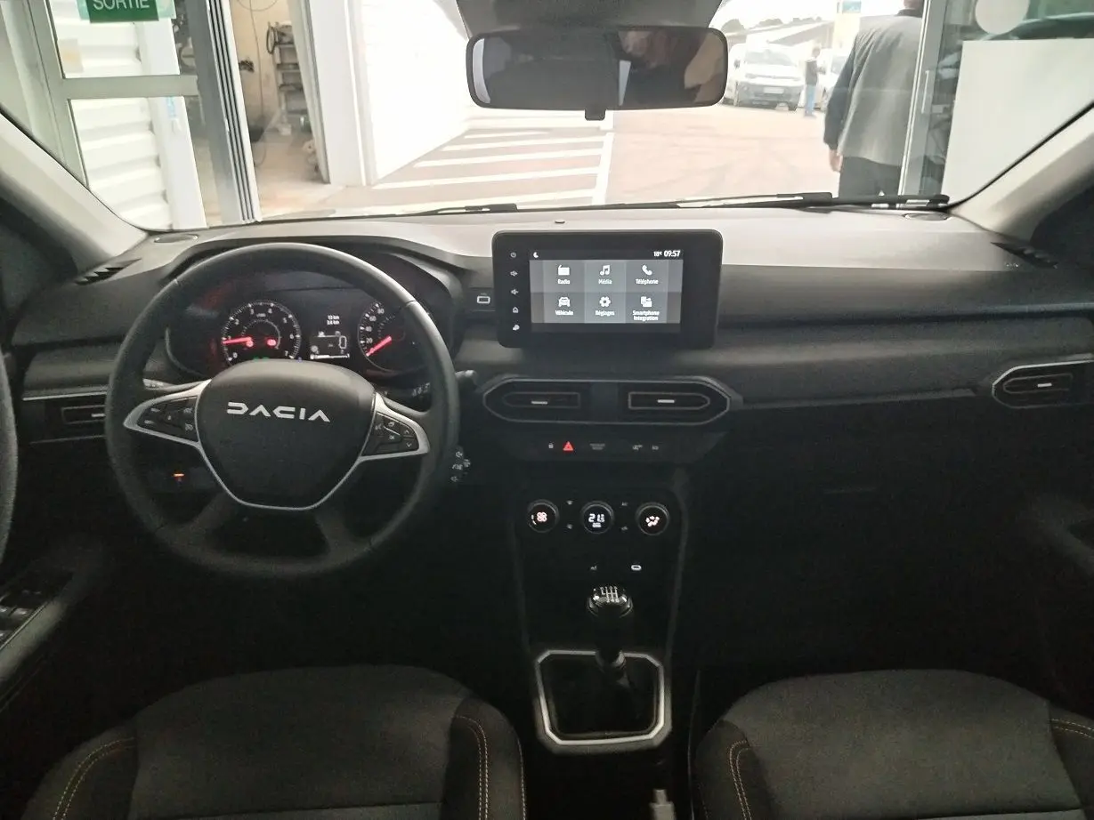 Intérieur du Dacia Jogger 2025, vue frontale du tableau de bord avec écran tactile et volant multifonction noir.