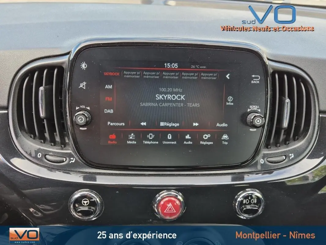 Vue rapprochée de l’écran central tactile et des commandes du tableau de bord noir du FIAT 500C 2024 hybride.