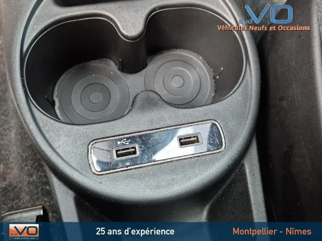 Gros plan sur la console centrale avec porte-gobelets et deux ports USB de la FIAT 500C noire 2024.