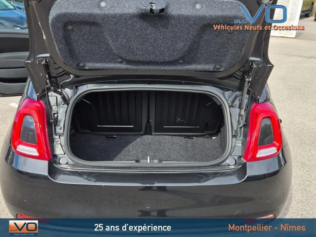 Vue arrière d'une FIAT 500C noire 2024 avec coffre ouvert, montrant l'espace de rangement et les feux arrière rouges.