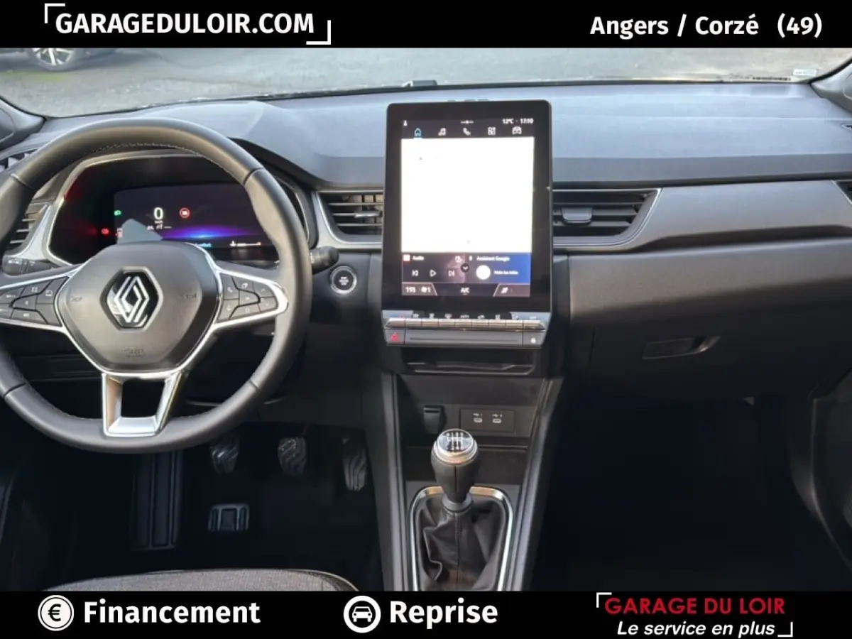 Vue intérieure du tableau de bord du Renault Captur 2025 gris foncé, avec volant multifonction et écran tactile vertical central.