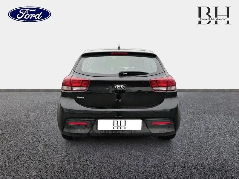Vue arrière d'une KIA Rio noire Ébène de 2018, avec feux rouges et lunette arrière dégivrante visible.