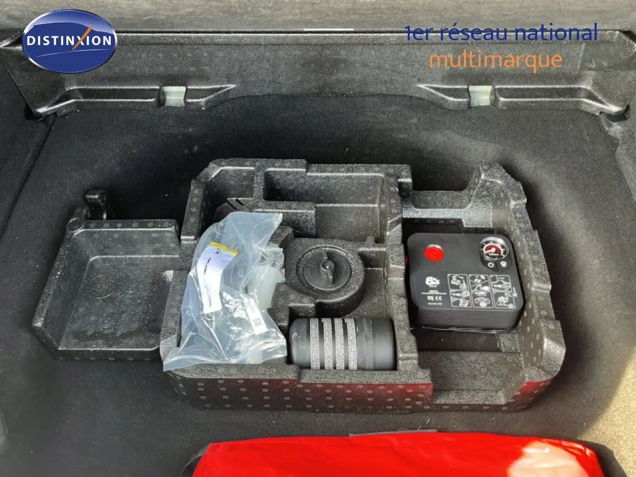 Coffre ouvert d’une Alfa Romeo Tonale gris Vesuvio, vue plongeante sur le rangement avec kit de réparation pneus.