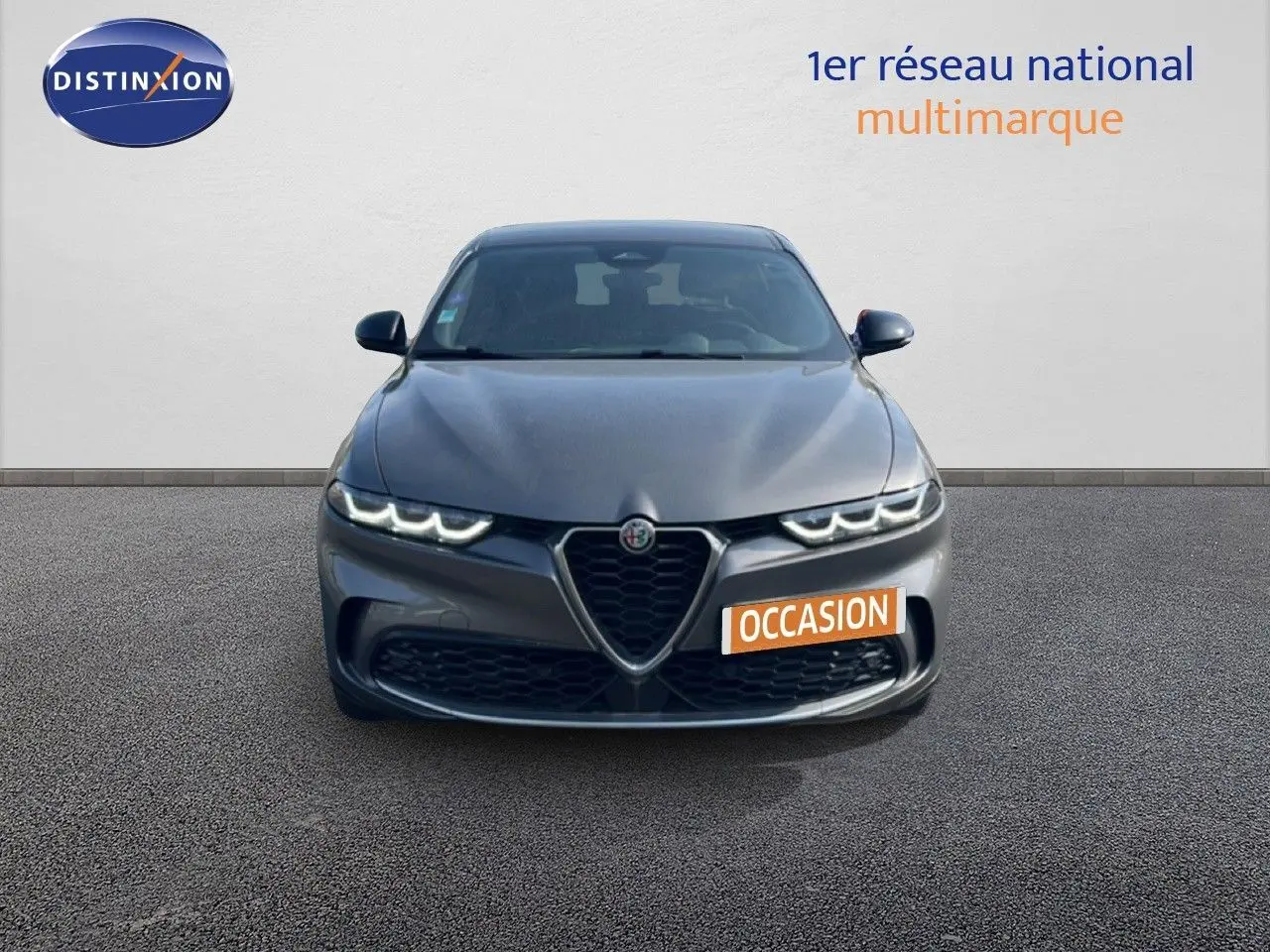 Vue de face de l'Alfa Romeo Tonale gris Vesuvio métal avec calandre caractéristique et phares LED allumés.