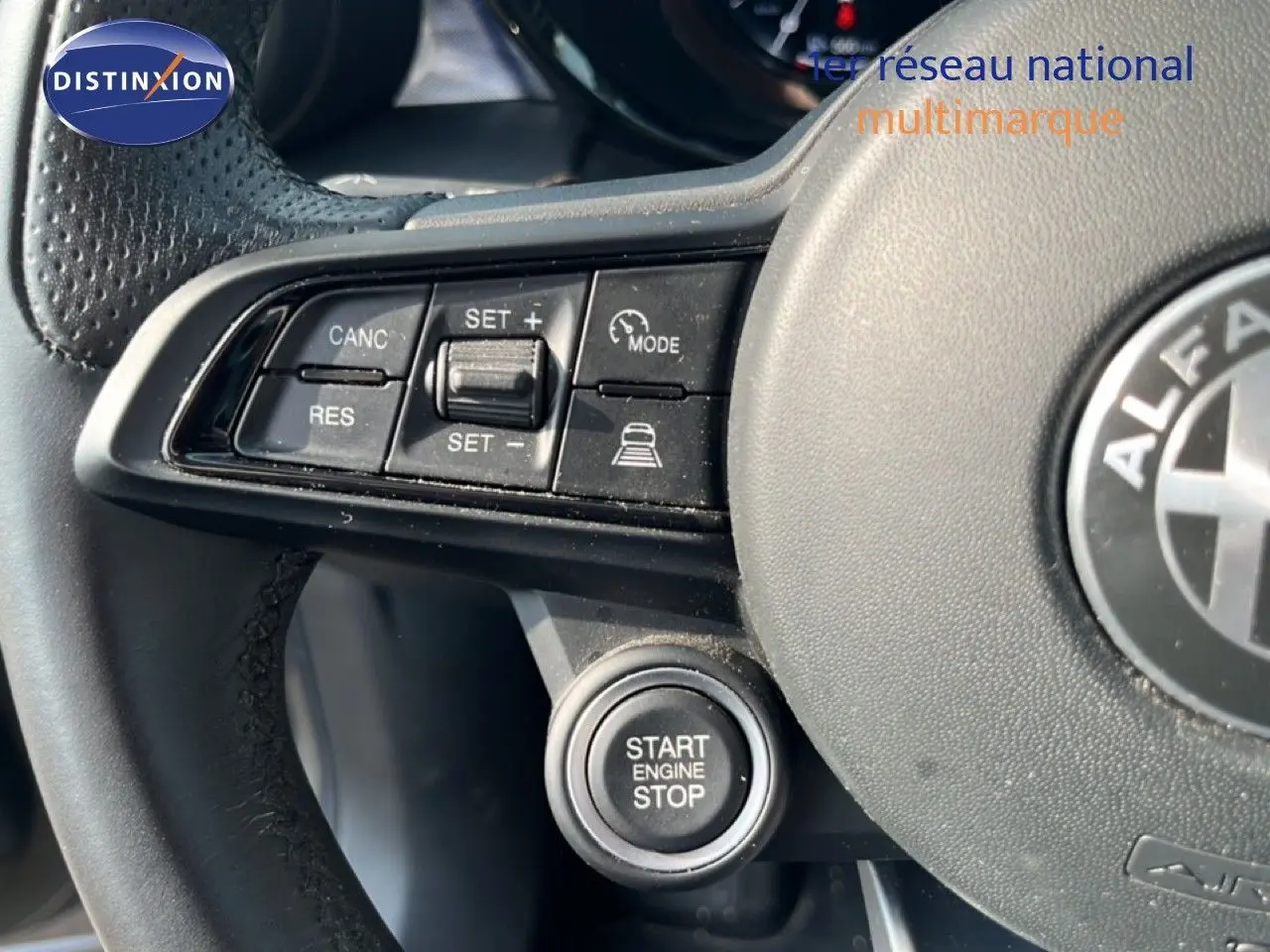 Gros plan sur le volant cuir noir de l'Alfa Romeo Tonale gris Vesuvio, avec commandes de régulateur et bouton start/stop visibles.