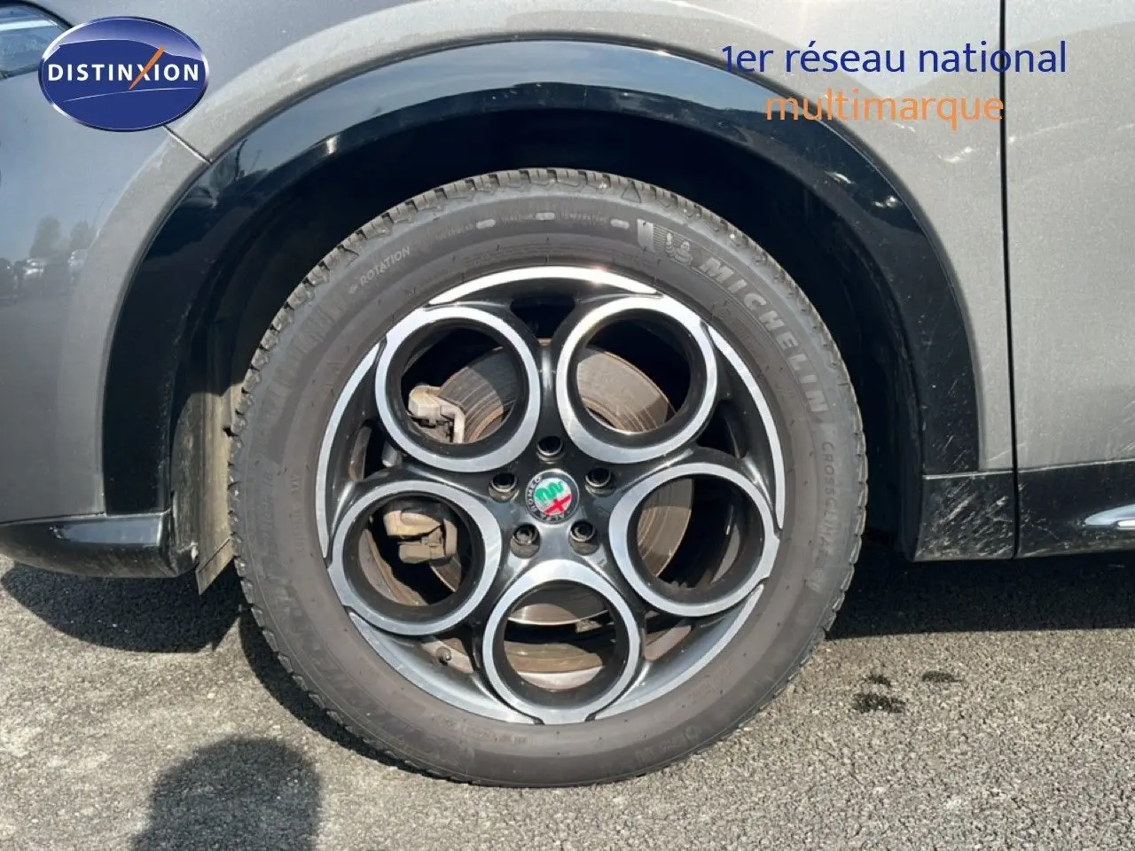 Gros plan sur la roue avant droite d'une Alfa Romeo Tonale gris Vesuvio métal avec jante en alliage à cinq cercles.