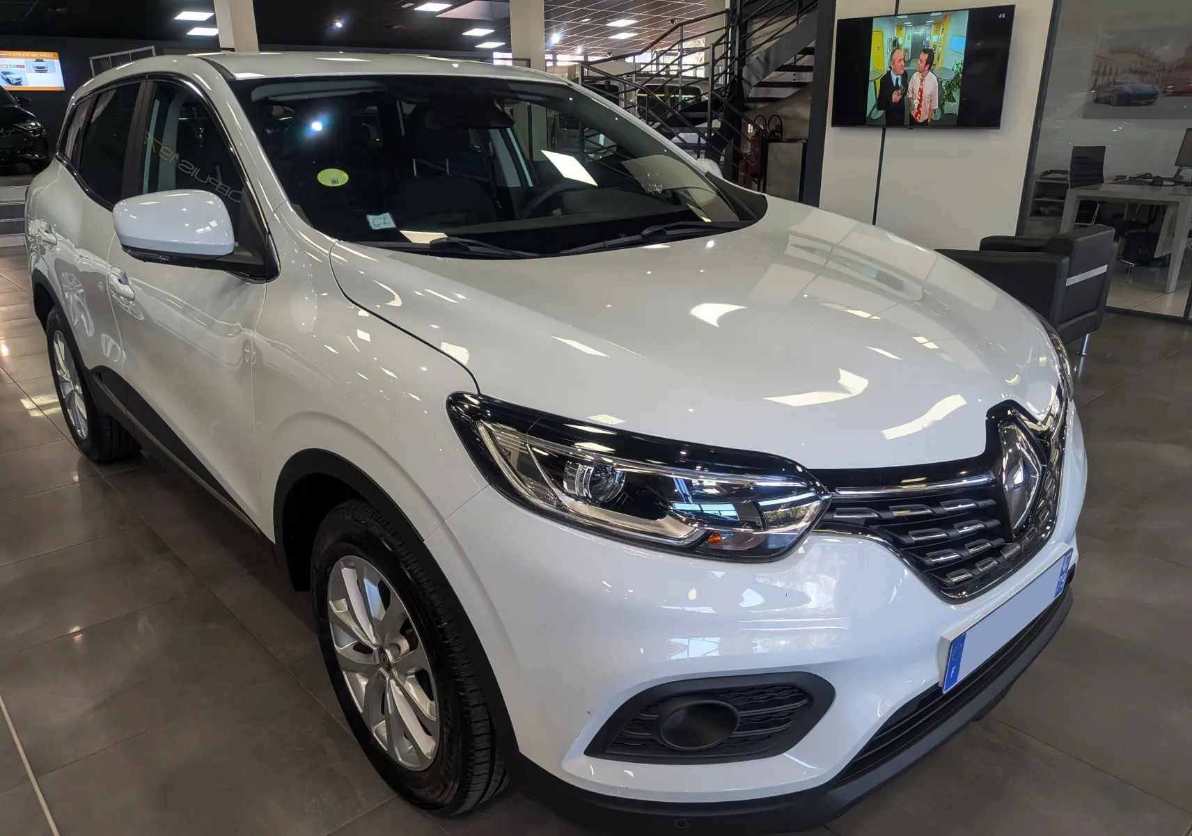 Renault Kadjar Blanc Glacier en 3/4 avant droit, mettant en valeur ses phares modernes et sa calandre noire brillante.
