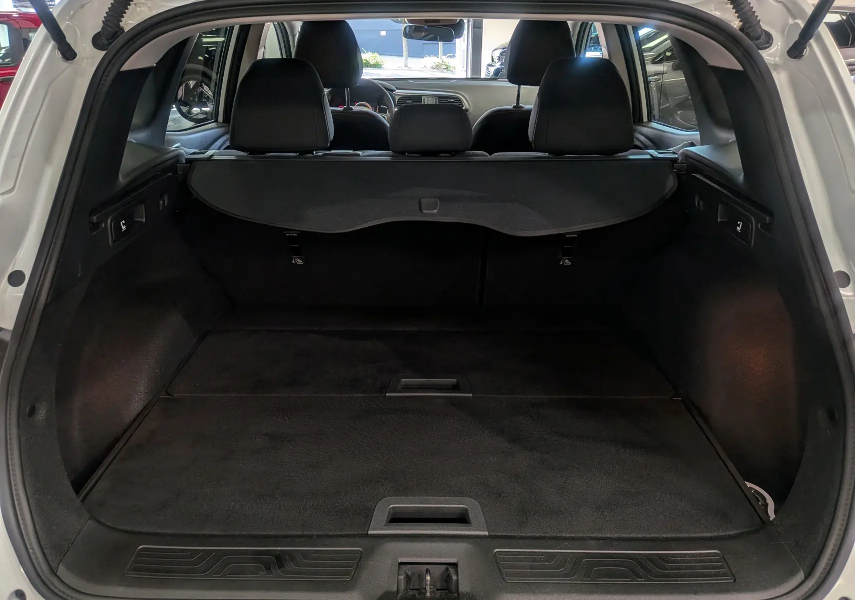 Coffre ouvert vu de l'arrière du Renault Kadjar Blanc Glacier 2021, montrant l'espace de chargement et les sièges arrière.