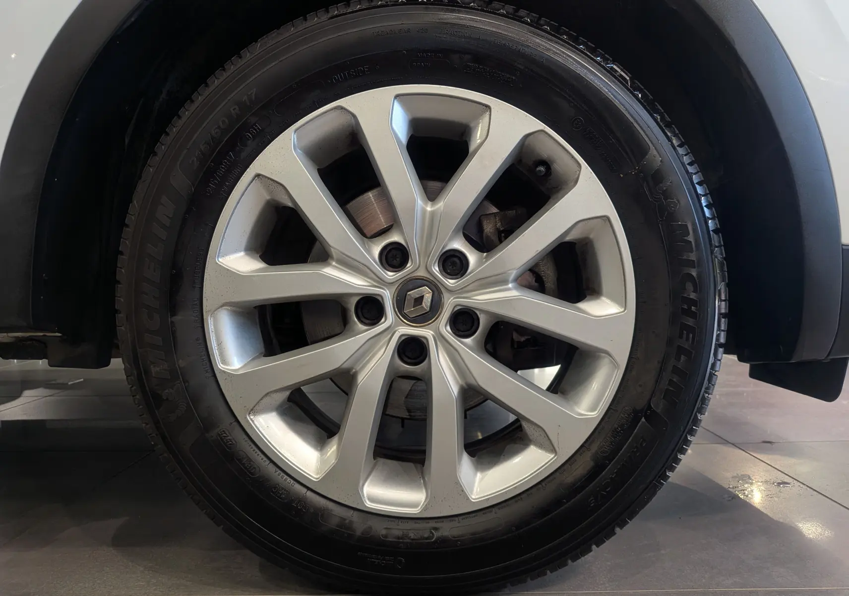 Gros plan sur la roue avant droite d’un Renault Kadjar blanc Glacier, jante alliage 17 pouces avec logo Renault central.