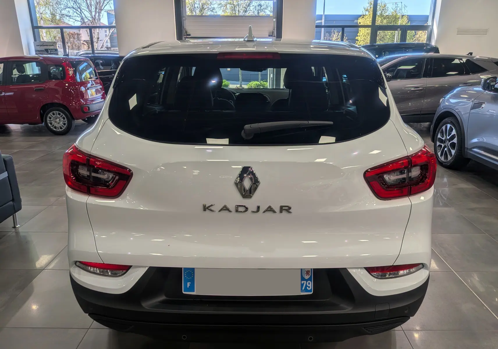 Vue arrière d'un Renault Kadjar blanc Glacier 2021 en showroom, avec feux arrière LED et lunette arrière teintée.