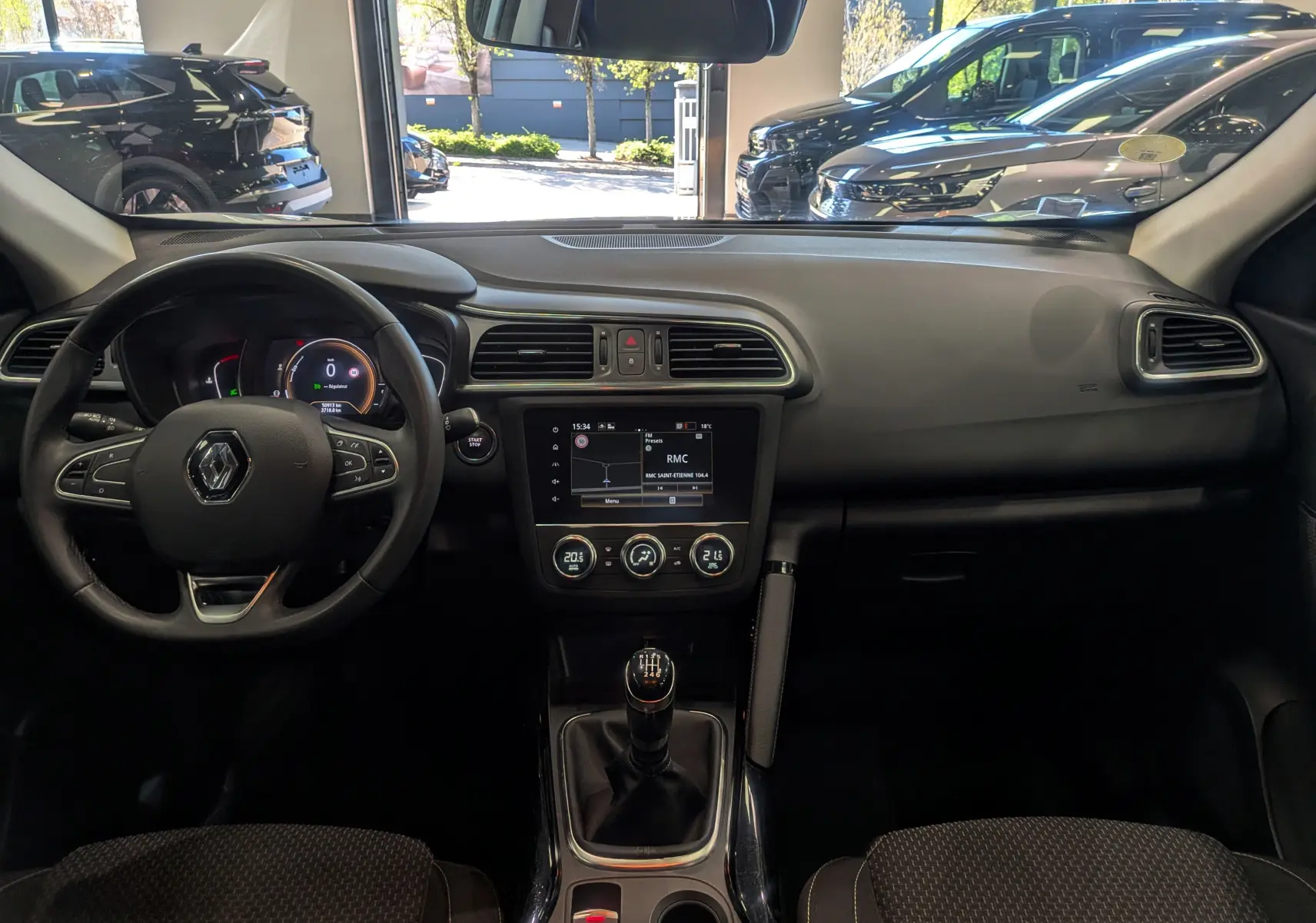 Vue intérieure avant du Renault Kadjar blanc Glacier 2021, tableau de bord avec écran tactile et boîte manuelle visible.