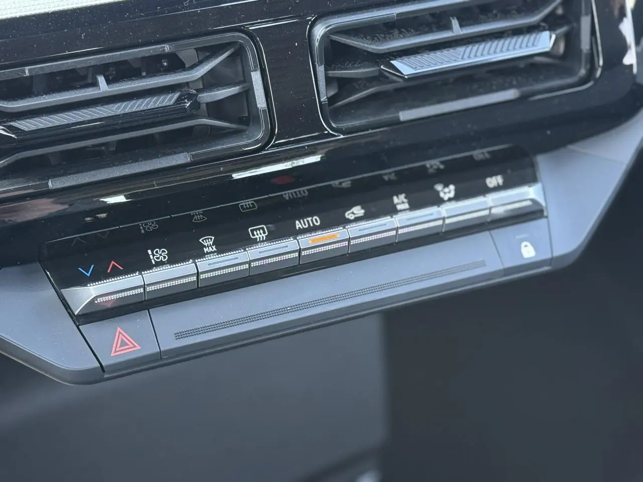 Gros plan sur la console centrale noire de la Renault R5 E-Tech avec commandes climatisation et ventilation.